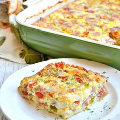 a slice of quiche on a white plate next to a green casserole dish