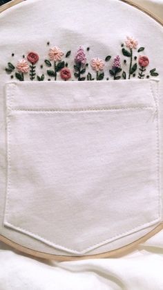 embroidered flowers are in the pocket of a white piece of cloth