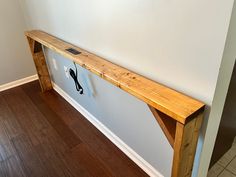 a wooden bench sitting on top of a hard wood floor next to a white wall