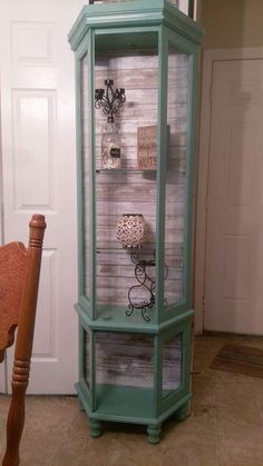 an old china cabinet is painted green and has decorative items on the glass shelves in front of it