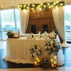 a table is set up with candles and flowers for a wedding reception in front of large windows