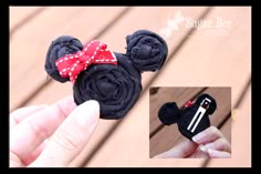 a hand holding a black mickey mouse hair clip with a red bow on it's head