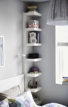 a bed sitting under a window next to a white book shelf filled with lots of books