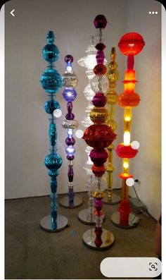 there are many different colored glass vases on the floor in front of a white wall