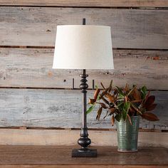 a table lamp sitting on top of a wooden shelf next to a potted plant