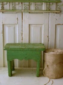 a small green bench sitting next to a wall with a basket on top of it