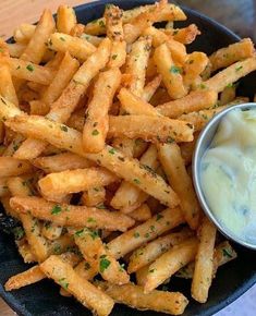 french fries are in a black bowl with a blue arrow pointing to the side and a small container of dip