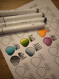 three markers are sitting on top of a sheet of paper that has been colored with different colors