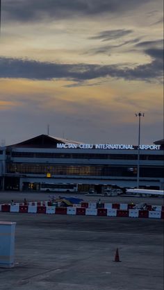 an airplane is sitting on the tarmac at dusk with cloudy skies in the background