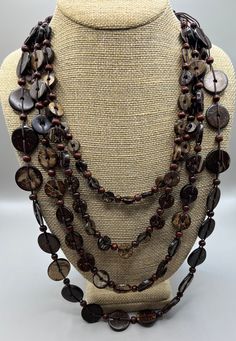 Featuring this lovely, tribal flair, coconut shell and wooden beaded necklace. The necklace is multi strand.   The shortest strand is 20", the longest is 30". The necklace is in very good vintage condition and has a button clasp. Bohemian Brown Shell Necklace With Wooden Beads, Traditional Brown Multi-strand Necklaces, Vintage Brown Necklaces For The Beach, Bohemian Brown Double Strand Necklace, Bohemian Brown Long Necklace With Round Beads, Brown Long Necklace For Beach, Bohemian Brown Shell Necklace With Round Beads, Artisan Double Strand Brown Necklace, Vintage Brown Beaded Necklaces For Beach