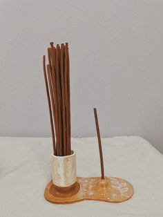 two vases with sticks sticking out of them on a white tablecloth covered surface