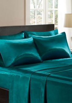 a bed with teal colored sheets and pillows