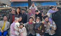 a group of people standing next to each other in front of a stone wall and building