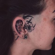 a woman with tattoos on her ear and behind the ear is a bird, butterfly and flower