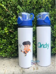 two children's water bottles sitting next to each other in front of some bushes