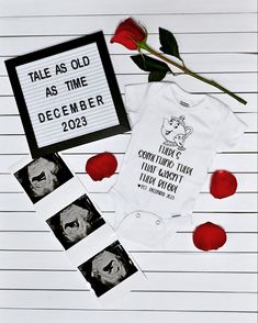 a baby's bodysuit and some photos are laying next to a rose