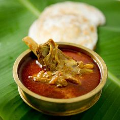 a small bowl filled with food on top of a green leaf