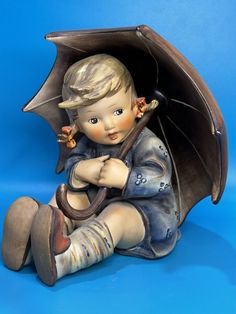 a figurine sitting on the ground holding an umbrella