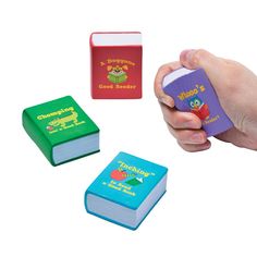 three children's books are being held in the air by a hand with an eraser