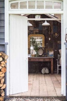 an open door leading into a room with wood stacked on the floor and a table