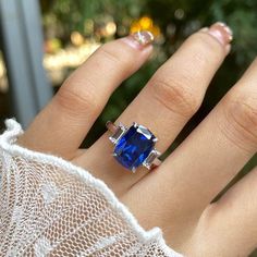 a woman's hand with a ring on it and a blue stone in the middle