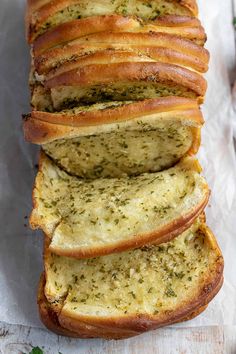 a loaf of garlic bread sliced and sitting on top of a piece of parchment paper