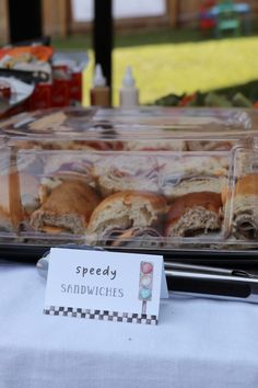 some sandwiches are sitting in a plastic container on a table with a sign that says speedy sandwiches