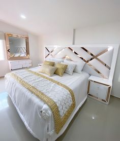 a large white bed sitting in a bedroom next to a dresser and mirror on the wall