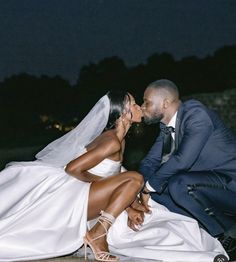 a bride and groom kissing each other on their wedding day in front of the night sky