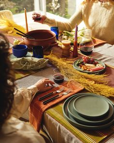 a woman sitting at a dinner table with plates and utensils