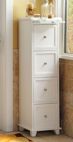 a white cabinet with three drawers in front of a window next to a yellow rug