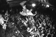 black and white photograph of a man on stage with guitar in front of an audience