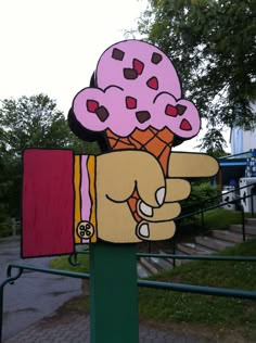 a hand holding an ice cream cone with hearts on it's head and pointing at the viewer