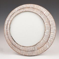 a white and gold plate sitting on top of a gray table next to a mirror