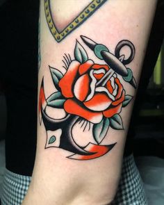 an anchor and rose tattoo design on the right arm, with scissors in the middle