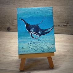 a painting of a manta ray dives into the ocean on an easel