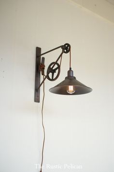 an old fashioned wall light hanging from the side of a white wall with a wire attached to it