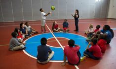 a group of people sitting on top of a basketball court with a ball in the air