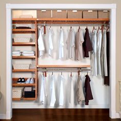 an open closet with clothes hanging on wooden shelves