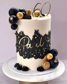 a black and white cake with gold decorations on it's top, sitting on a plate