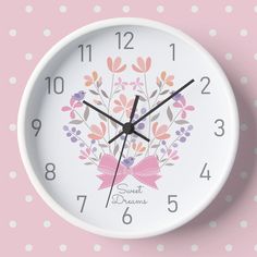 a white clock with pink and purple flowers on it's face against a polka dot background