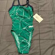 a green and white swimsuit laying on top of a bed next to a tag