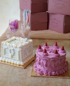 two cakes sitting next to each other on top of a wooden table in front of boxes