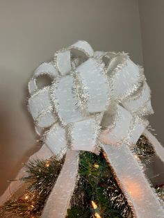 a white bow on top of a christmas tree