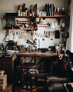 a workbench with lots of tools hanging on the wall and shelves above it