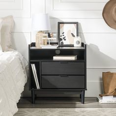 a nightstand with a hat on top of it next to a bed