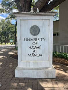 the university of hawaii at manoa monument is shown in front of a large tree