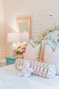 a white bed with pink and green pillows