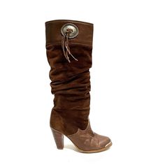 Vintage 1980s Women’s Brown Suede High Heel Knee High Western Slouch Boots By Zodiac. Features Brown Suede Uppers, Brown Leather Foot Box And Top Of Shaft, Rounded Toe With Silver Tone Logo Engraved Toe Plate, Knee High Rise, Slouchy Shaft, Western Style Silver Medallion With Suede Tassels At Top Of Shaft, Logo Fabric Lining, Flat Tops, Pull On Style, And Slanted Wooden Cone Heel. Excellent Vintage Condition. Made In The Usa. Heel To Toe (Inside Shoe): 9.125 Inches Ball Of Foot (Bottom Of Sole): 70s Boots, 1980s Women, Slouch Boots, Slouchy Boots, Inside Shoes, Suede High Heels, Suede Tassel, Slouched Boots, Vintage Belts