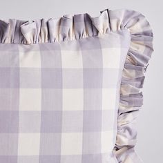 a pillow with ruffles on it sitting next to a gray and white checkered pillow